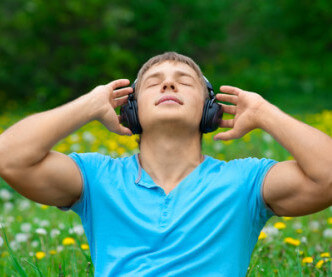 self soothing listening to music in headphones sitting on grass.