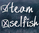 Signs of your own narcissism: Selfish ticked on blackboard and team crossed off.