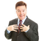 Businessman looking surprised and pointing to himself as if to say "who me?" Isolated on white.